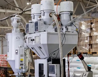 Hopper dryers, material loaders and gravimetric blender above a plastics extruder